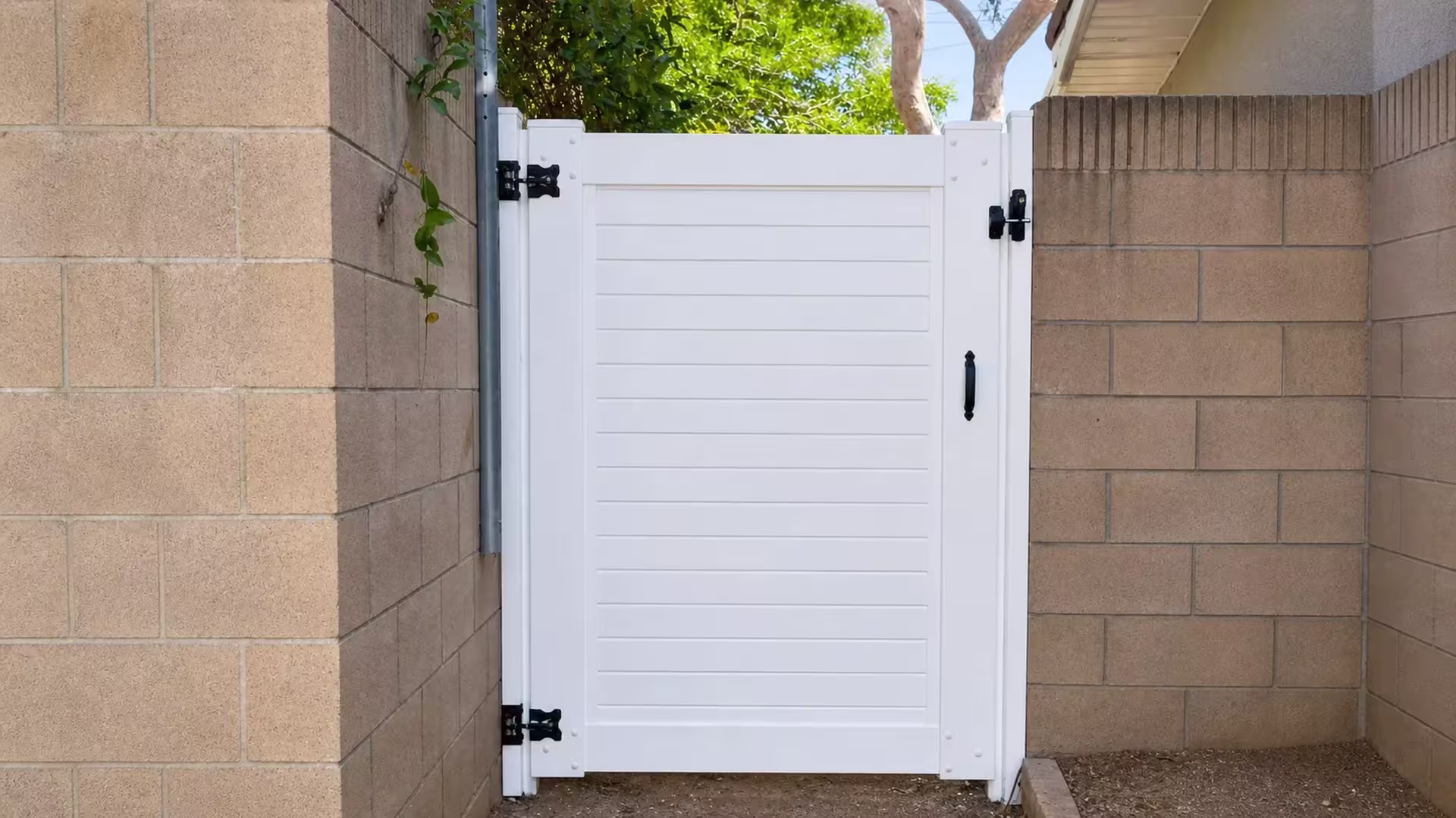 White vinyl side gate with horizontal board courses fitted tightly between two tan concrete block walls