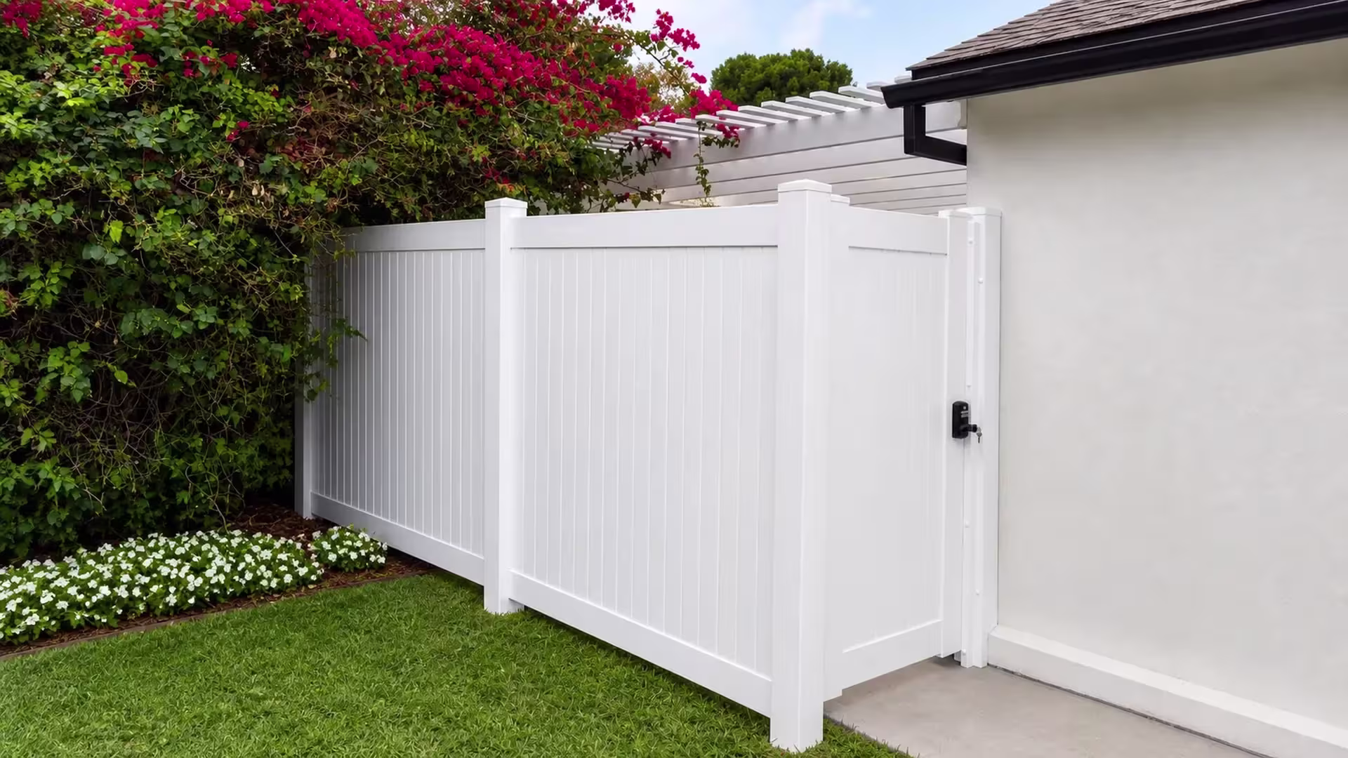 A black keypad latch secures this White vinyl side gate beside a light stucco house and its matching fence run
