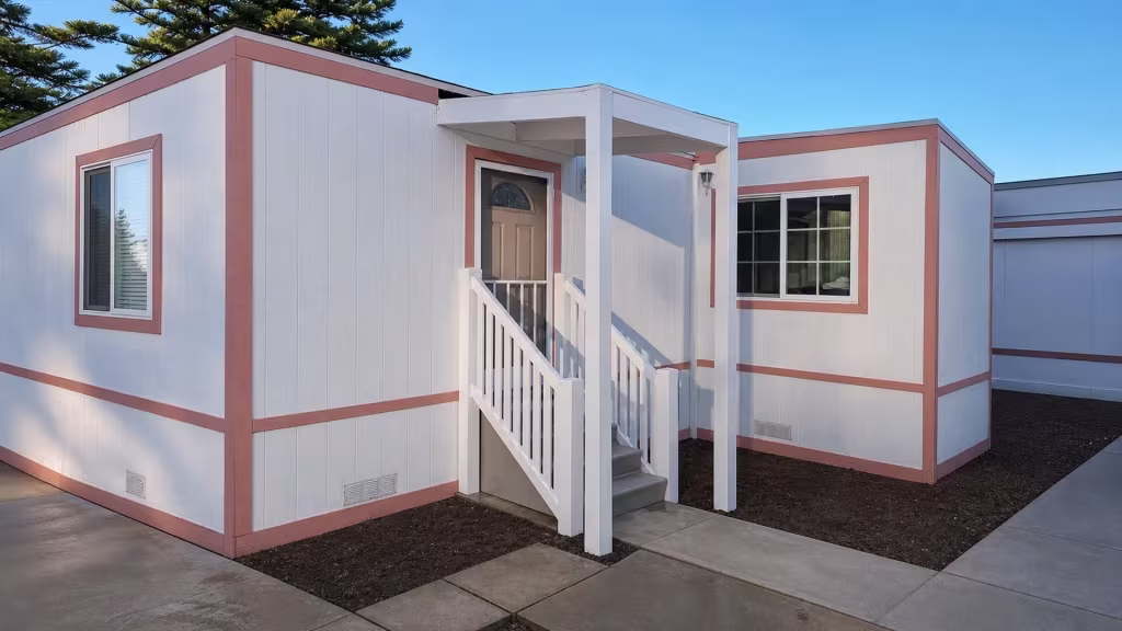 Concrete steps climb to the entry landing where the White vinyl cover meets pink trimmed siding and lanterns