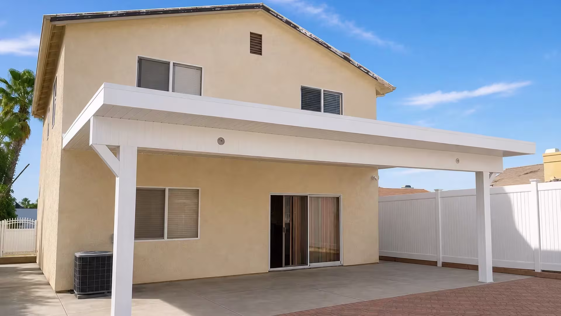 Patterned foreground pavers lead toward the White vinyl cover fixed on a two story beige stucco exterior
