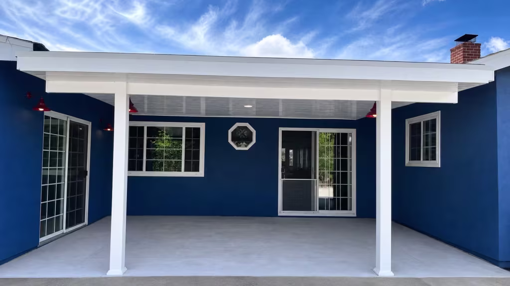 Red hanging light fixtures hang beneath this White vinyl solid patio cover fixed to a dark blue stucco house