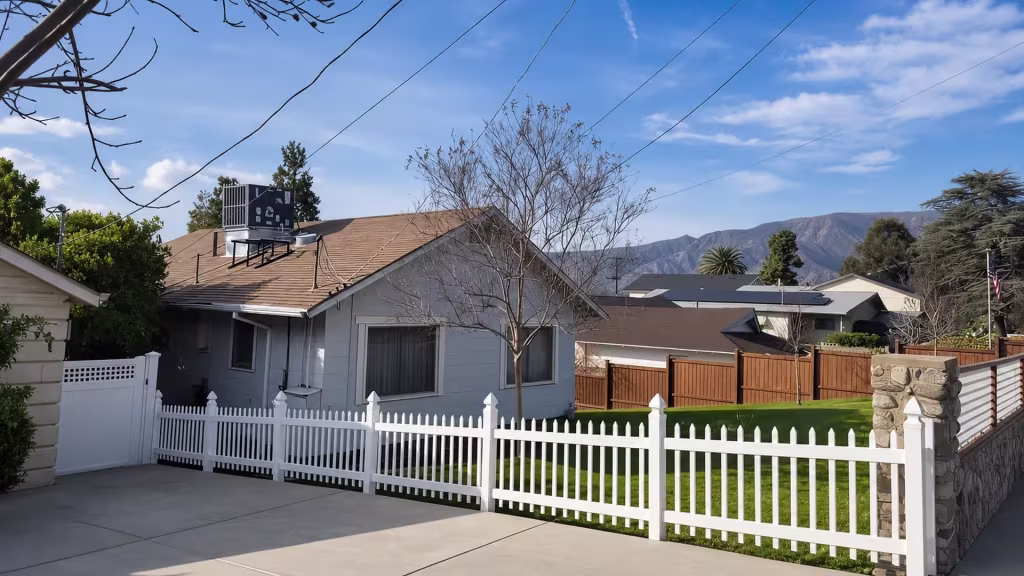 Five White vinyl picket fence bays step down gradually to match a sloped front yard grade