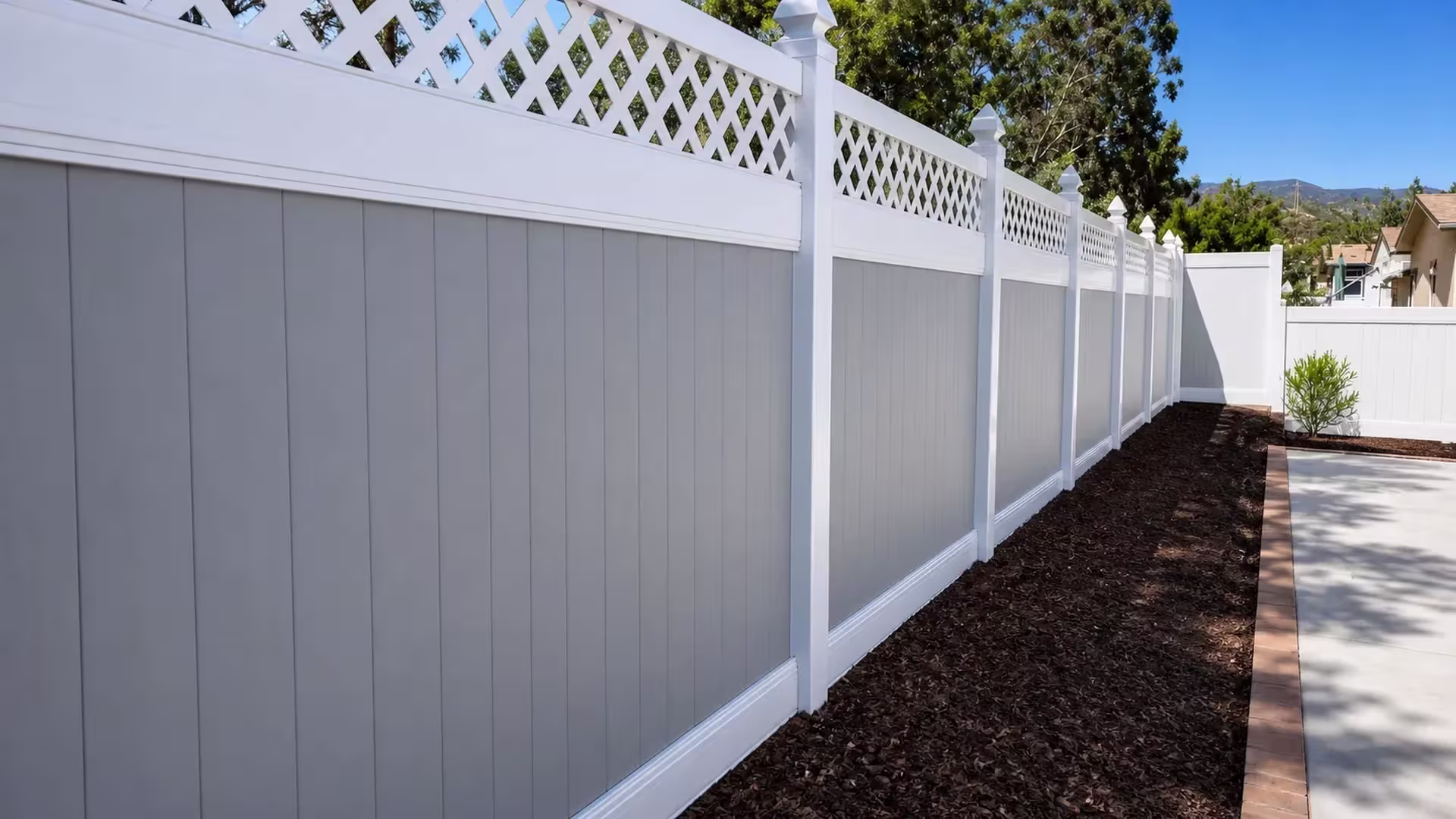 White vinyl two-tone fence topped with a diamond lattice section above a brick patio