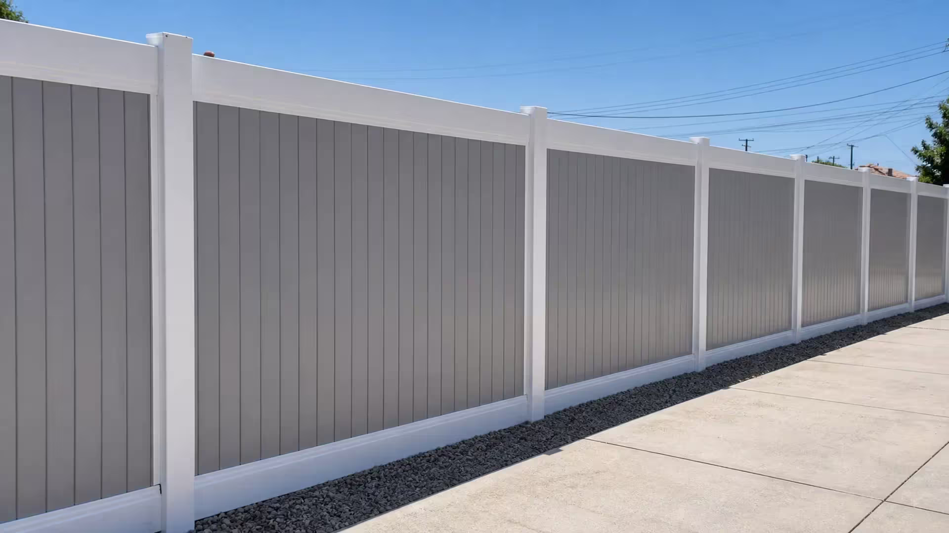 The gravel strip runs beside a gray-boarded White vinyl two-tone fence and posts