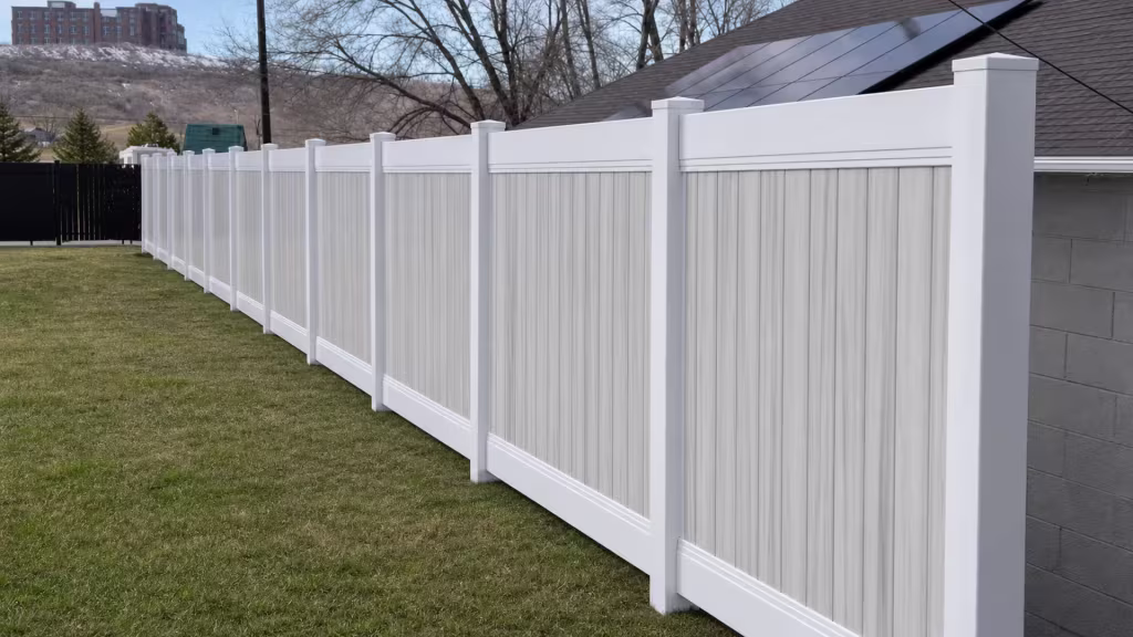 A garage roofline rises beside the White vinyl two-tone fence receding into the yard