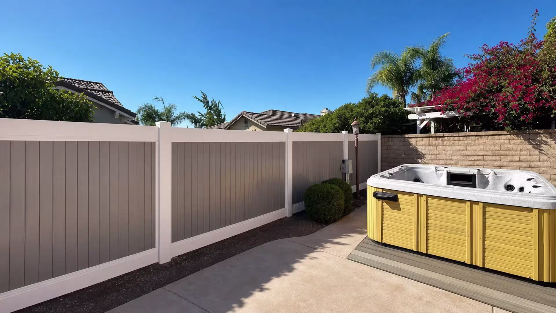 Two-tone Tan vinyl privacy fence spanning three panels that end at a masonry boundary post