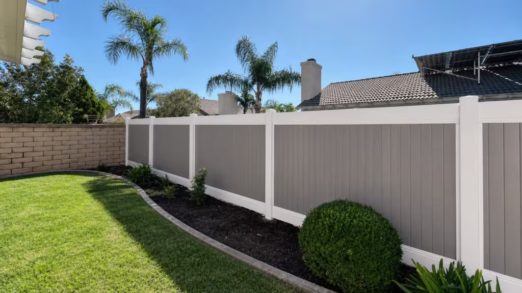 Curved planting-bed edging borders a Tan vinyl two-tone fence in a rear garden