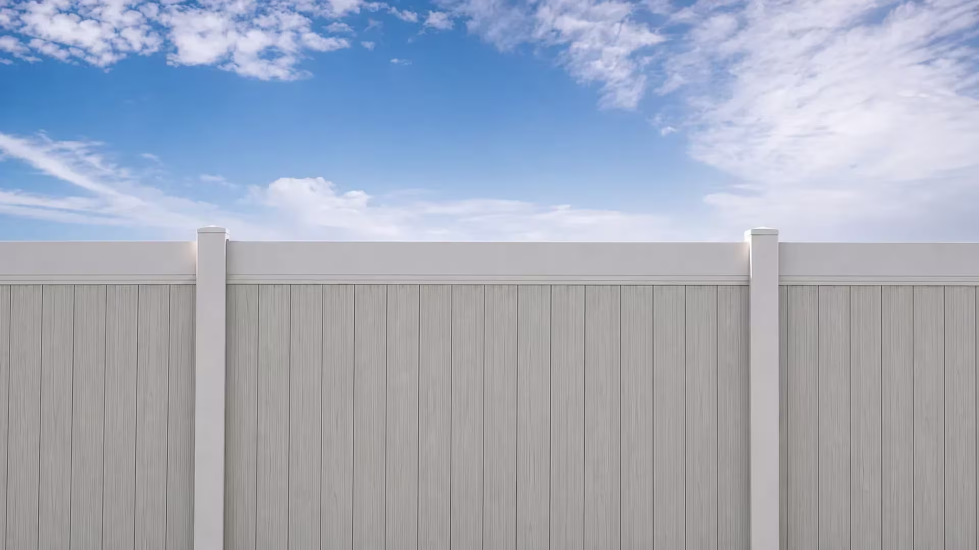 White vinyl two-tone fence panel framed between two square posts with pyramidal caps
