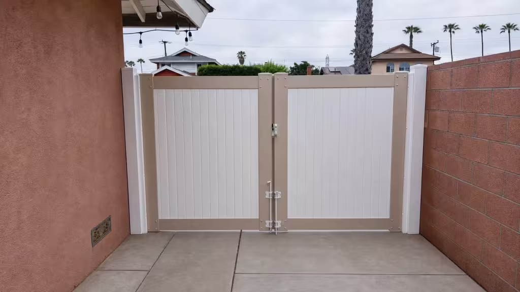 White two-tone vinyl gate closed between a stucco house wall and a masonry block wall