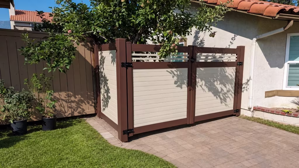 An angled return panel joins this Beige two-tone vinyl driveway gate beside potted plants