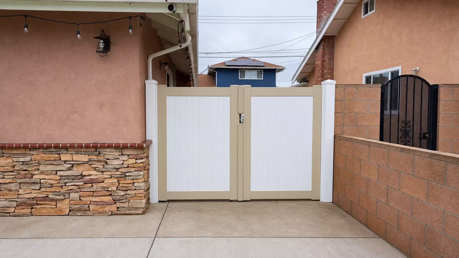 White square posts with pyramid caps support this Tan two-tone vinyl driveway gate
