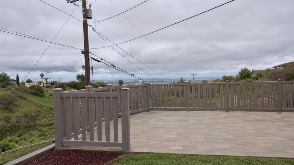 A closed-top picket run in Weathered Blend vinyl bends behind diagonal bracing near this gated tiled-patio fence section