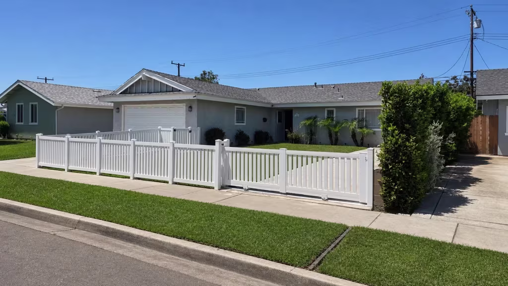 Six posts carry this White vinyl picket fence to a two-leaf driveway gate meeting at a center seam