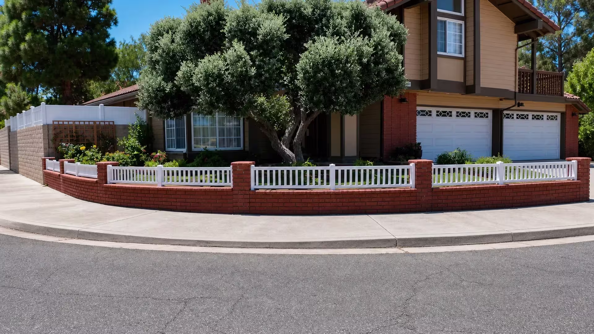 Seven bays of White vinyl picket fence curve gently along the top of a red-brick front-yard wall