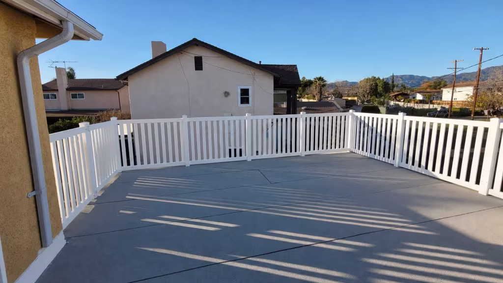 Patch outlines mark a raised patio slab where a White vinyl picket fence wraps three connected runs