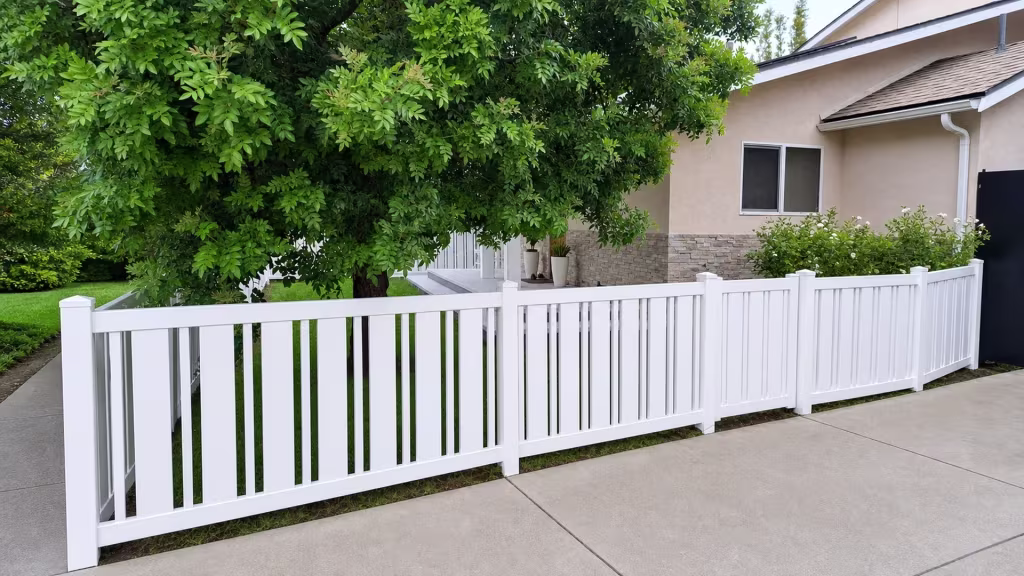 A pedestrian gate centered on the walkway divides this White vinyl picket fence into five sections
