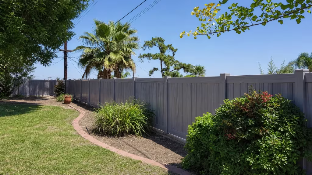 This Coastal Cedar vinyl privacy fence runs diagonally past a terracotta planter and a curved brick garden path