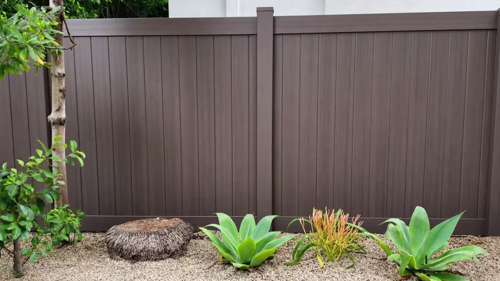 A single central post divides two bays of this Dark Walnut vinyl privacy fence with narrow vertical boards