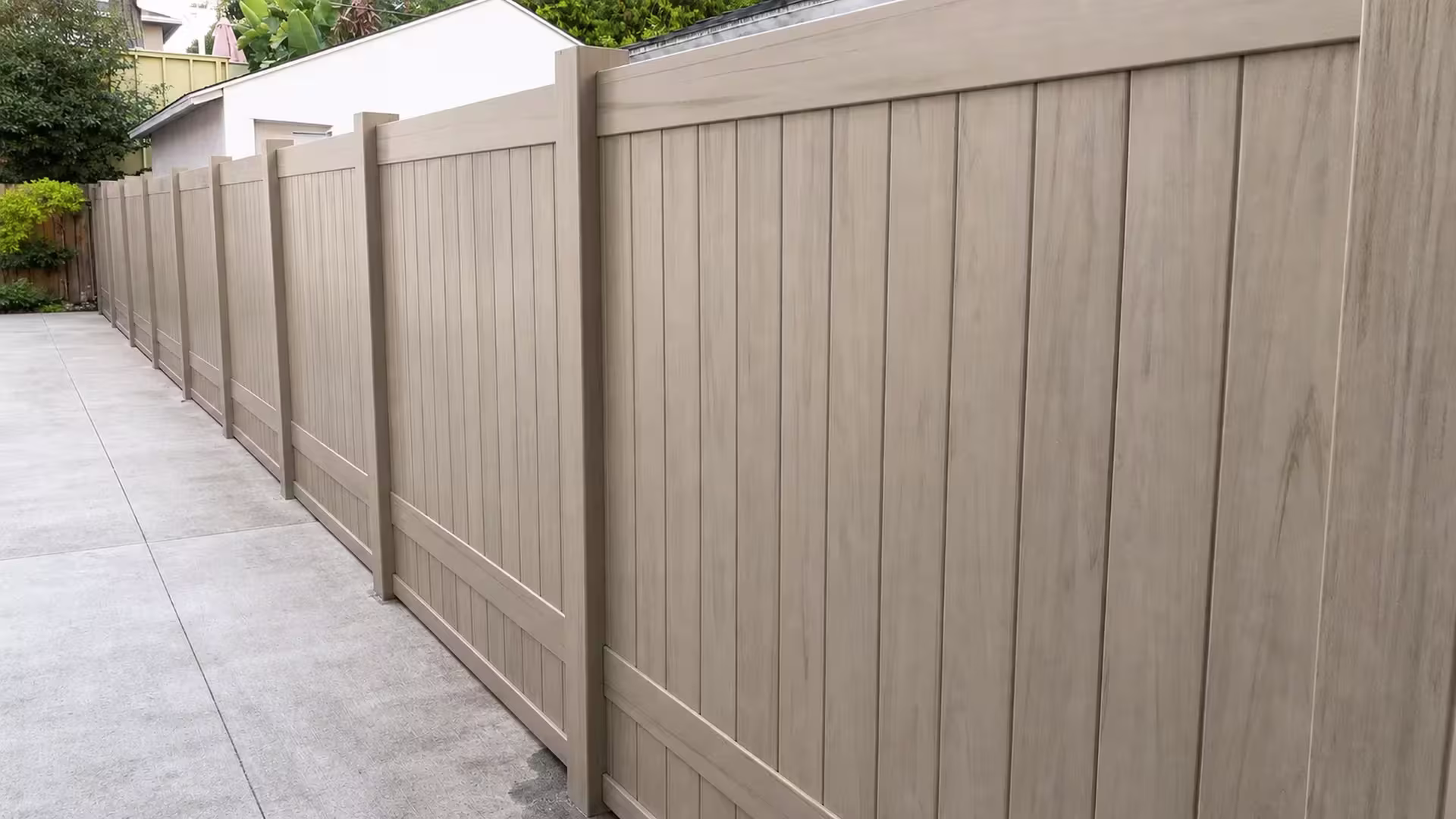 This Mesquite vinyl privacy fence recedes from the yard toward a white outbuilding and adjoining garage structures