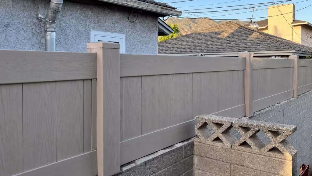 Mesquite vinyl vertical privacy fence topping a gray block wall above decorative openwork concrete blocks