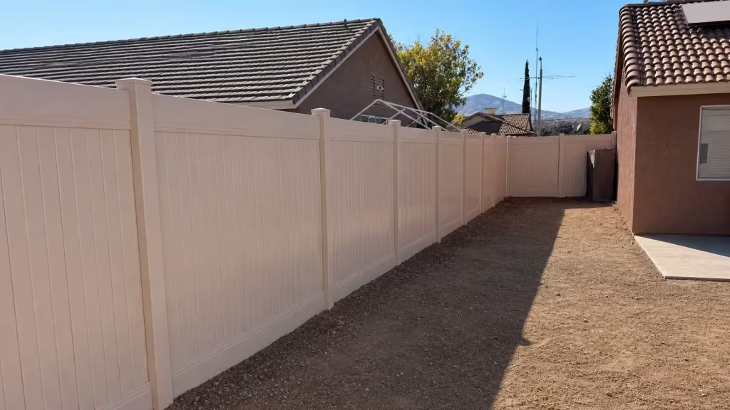 Long Tan vinyl vertical privacy fence stretching toward the rear yard beneath distant mountains