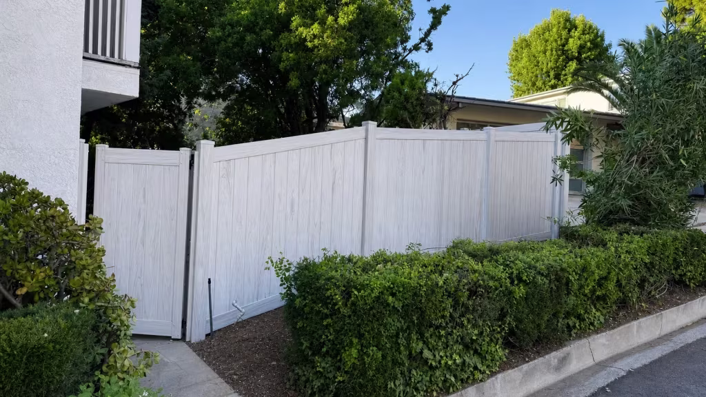 A narrow gate leaf leads this Weathered Aspen vinyl privacy fence past a barred stucco wall opening