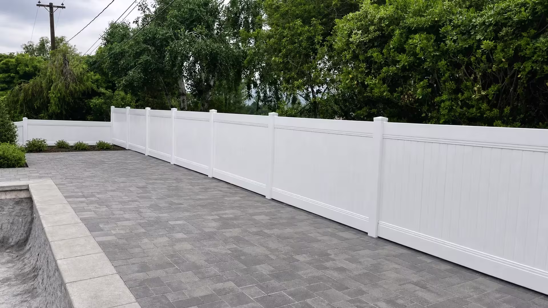 Smooth White vinyl vertical privacy fence bends at a corner post into a shorter return near a pool