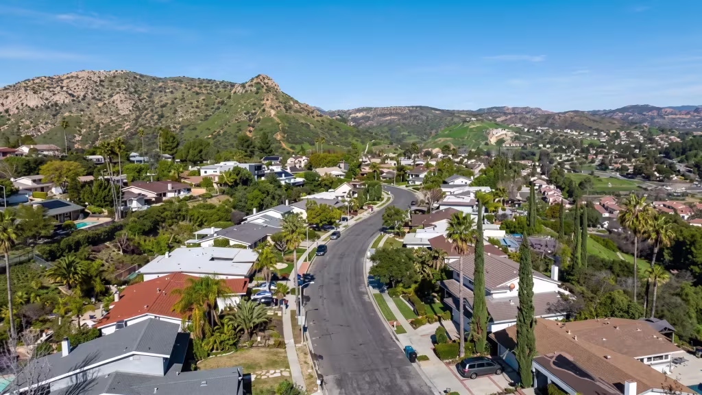 A hillside residential neighborhood in West Hills opens onto the wider city beyond, from an elevated oblique angle