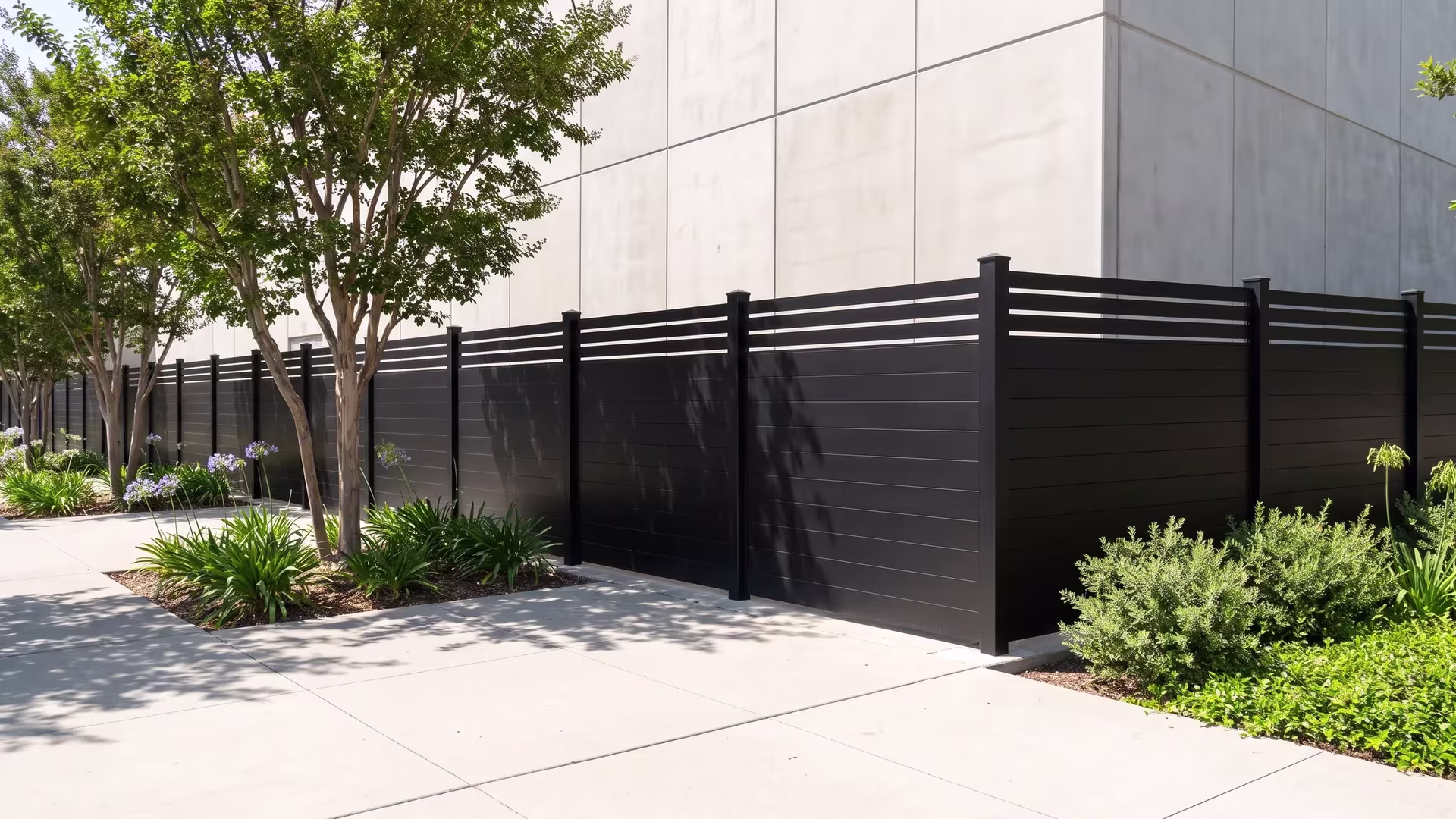 Black aluminum privacy fence with a picket top screening a windowless data center equipment hall