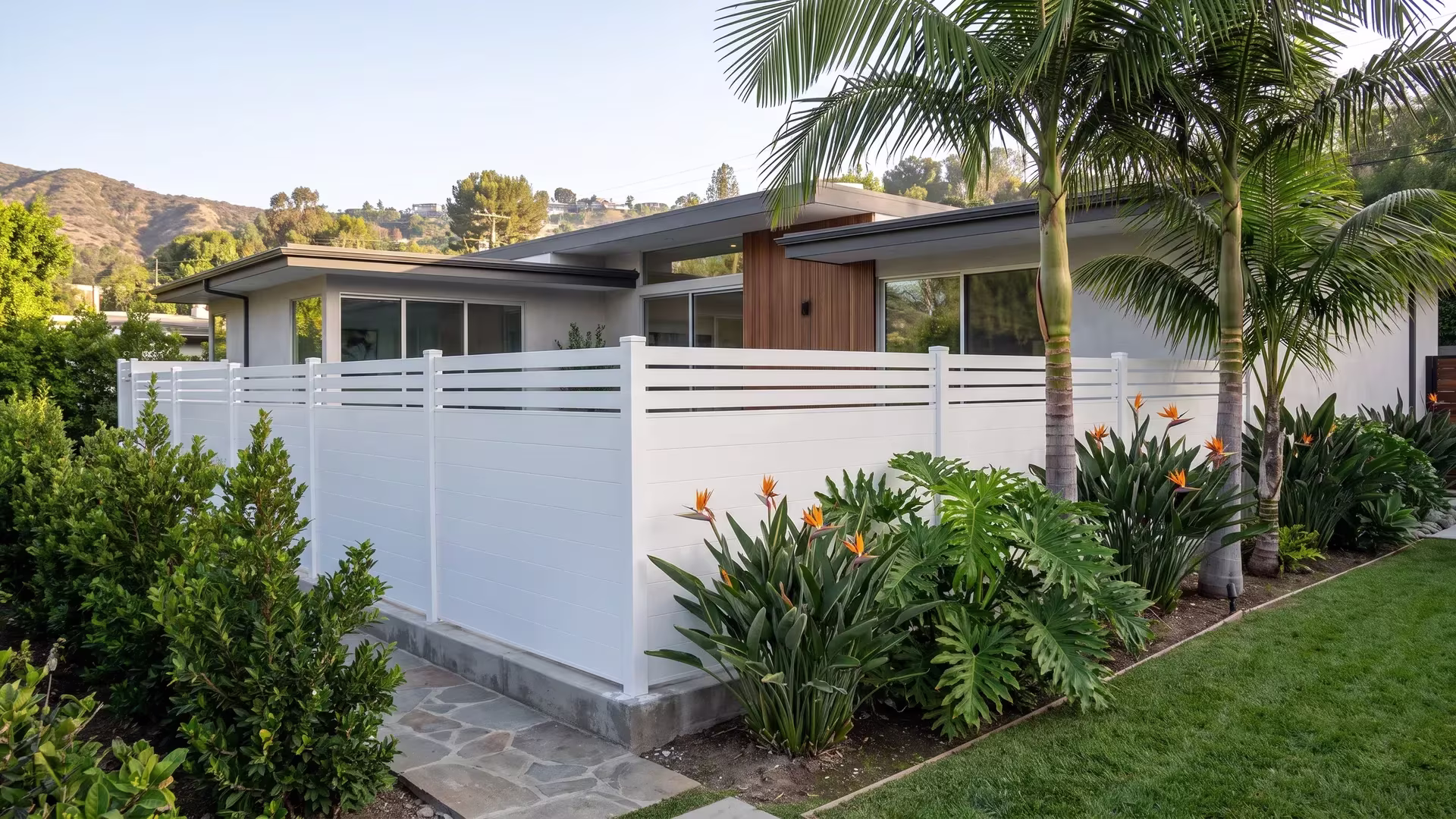 White aluminum privacy fence turning across a terrace beside a narrow flagstone walk