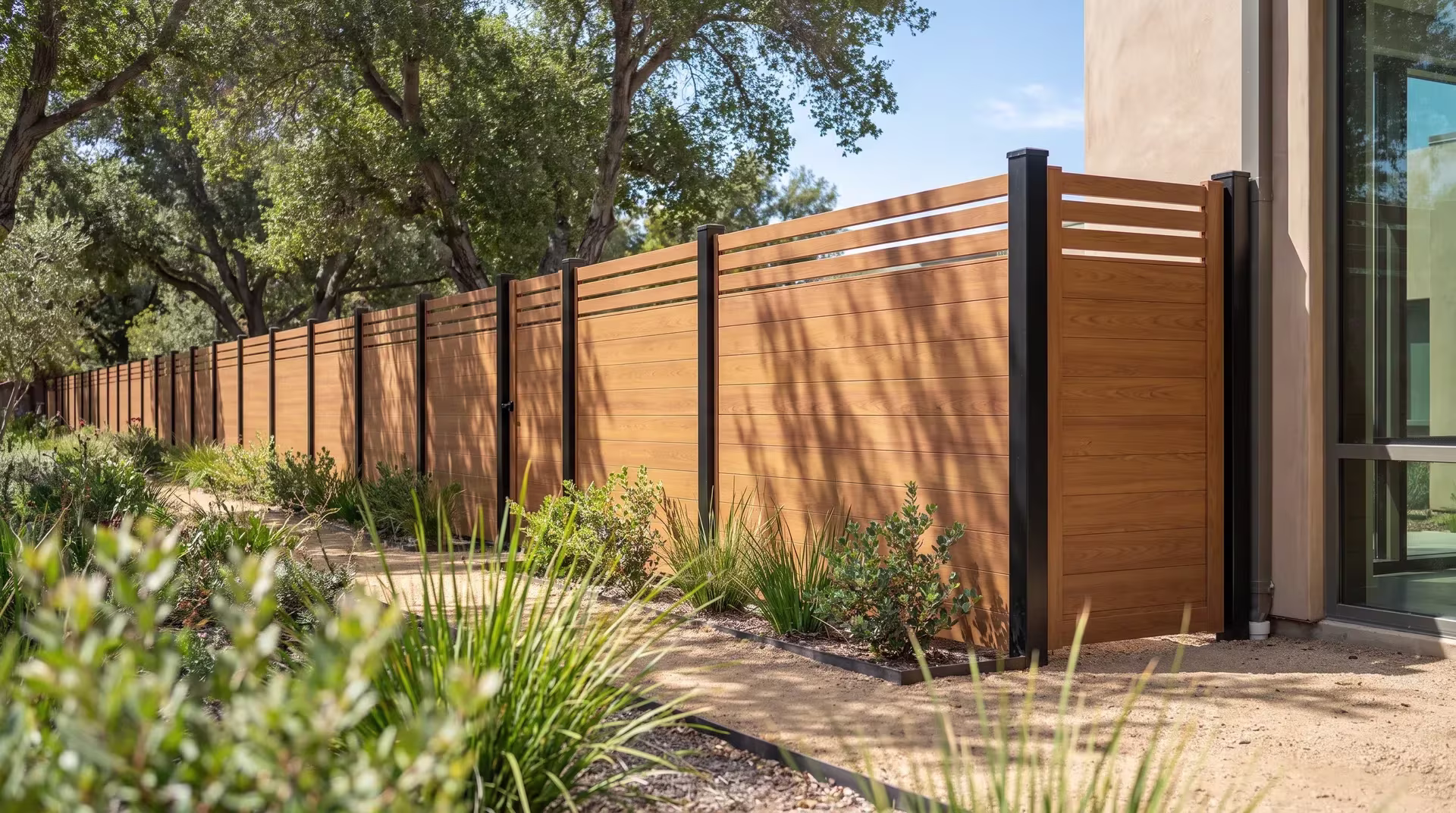 Manzanita and lomandra fill the swales beside this Woodgrain aluminum privacy fence at a medical office campus
