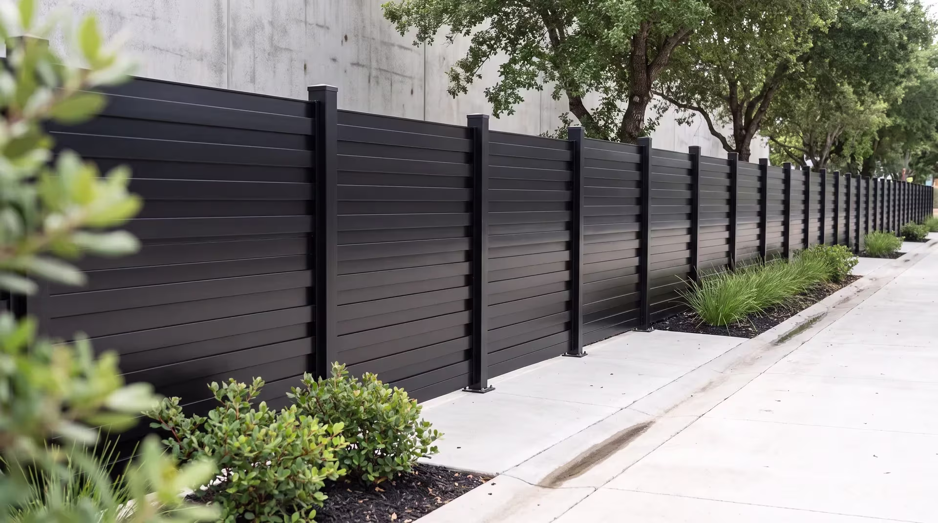 Concrete drainage channels edge this aluminum horizontal privacy shadowbox fence at a design studio courtyard