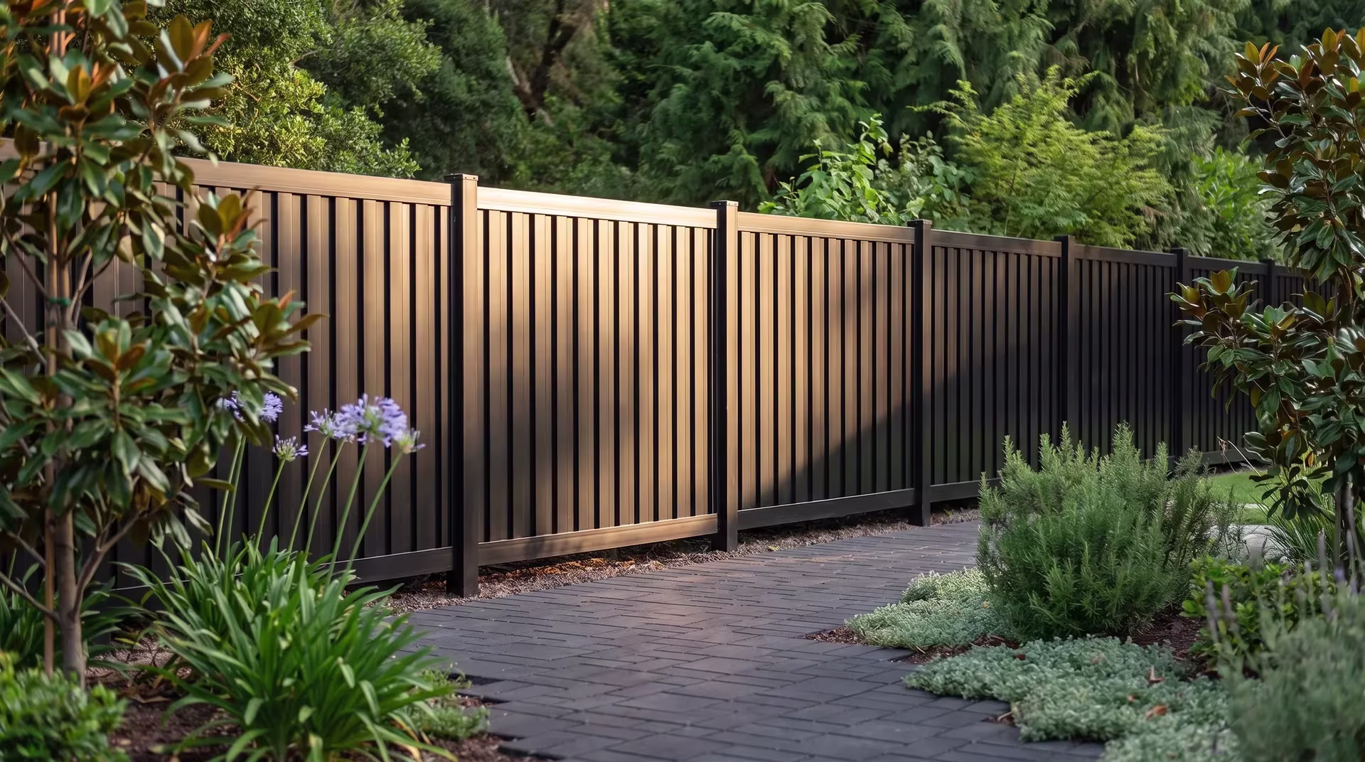 Dark charcoal pavers and rosemary surround this aluminum vertical privacy shadowbox fence at a canyon home, in Black