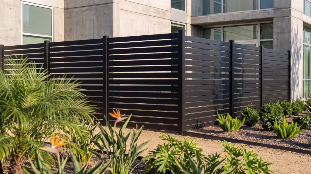 Decomposed granite with crisp steel edging meets this Black aluminum semi privacy fence at a shallow property line turn