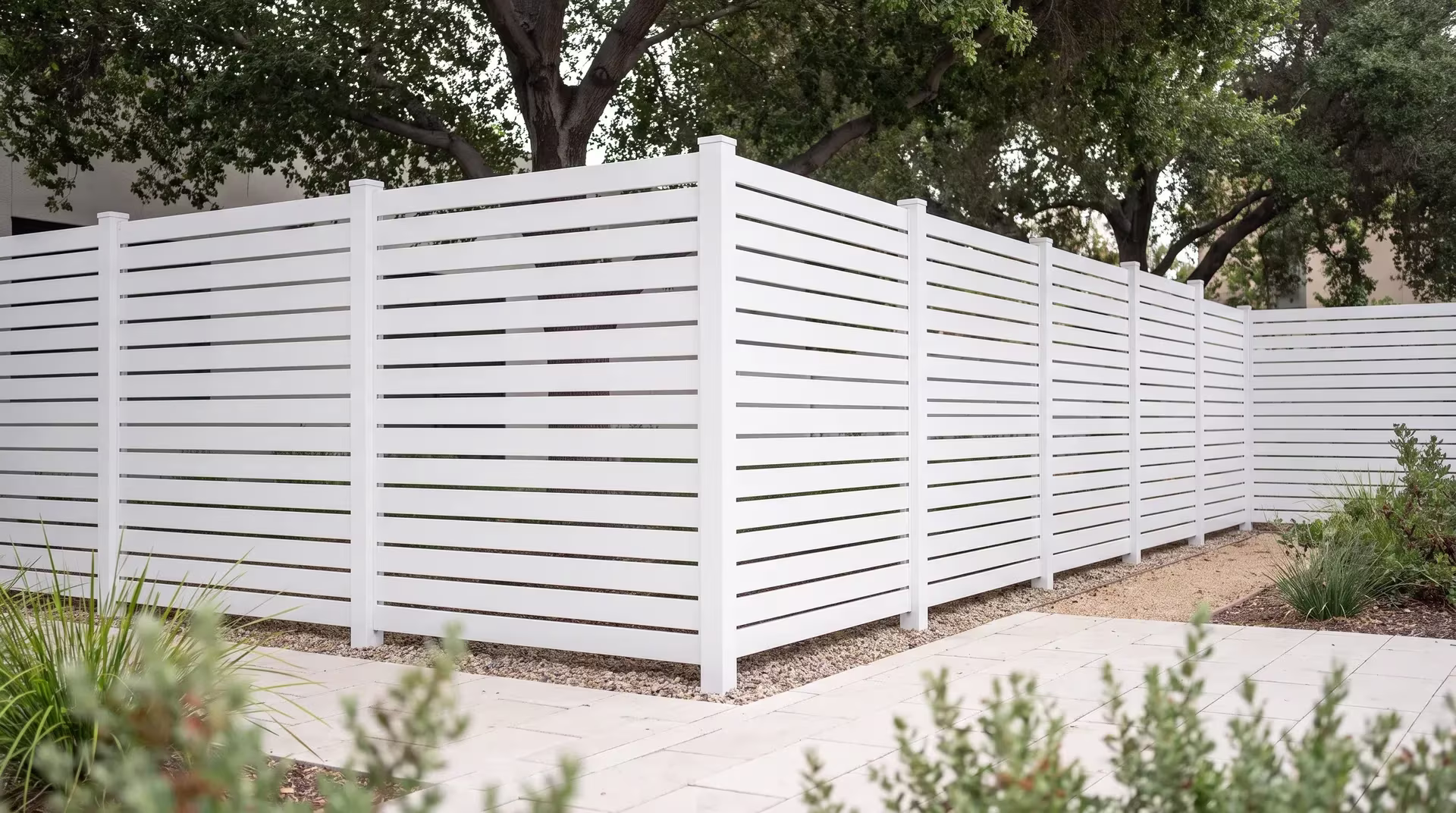 Pale stone paving and a narrow gravel band trace this White aluminum semi privacy fence along a coworking courtyard edge