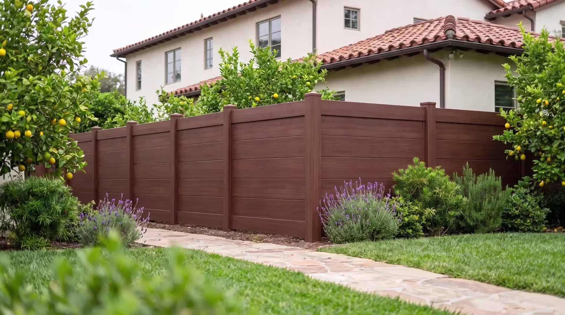 A narrow flagstone walk passes this Brazilian Blend vinyl horizontal privacy run on a terraced hillside lawn