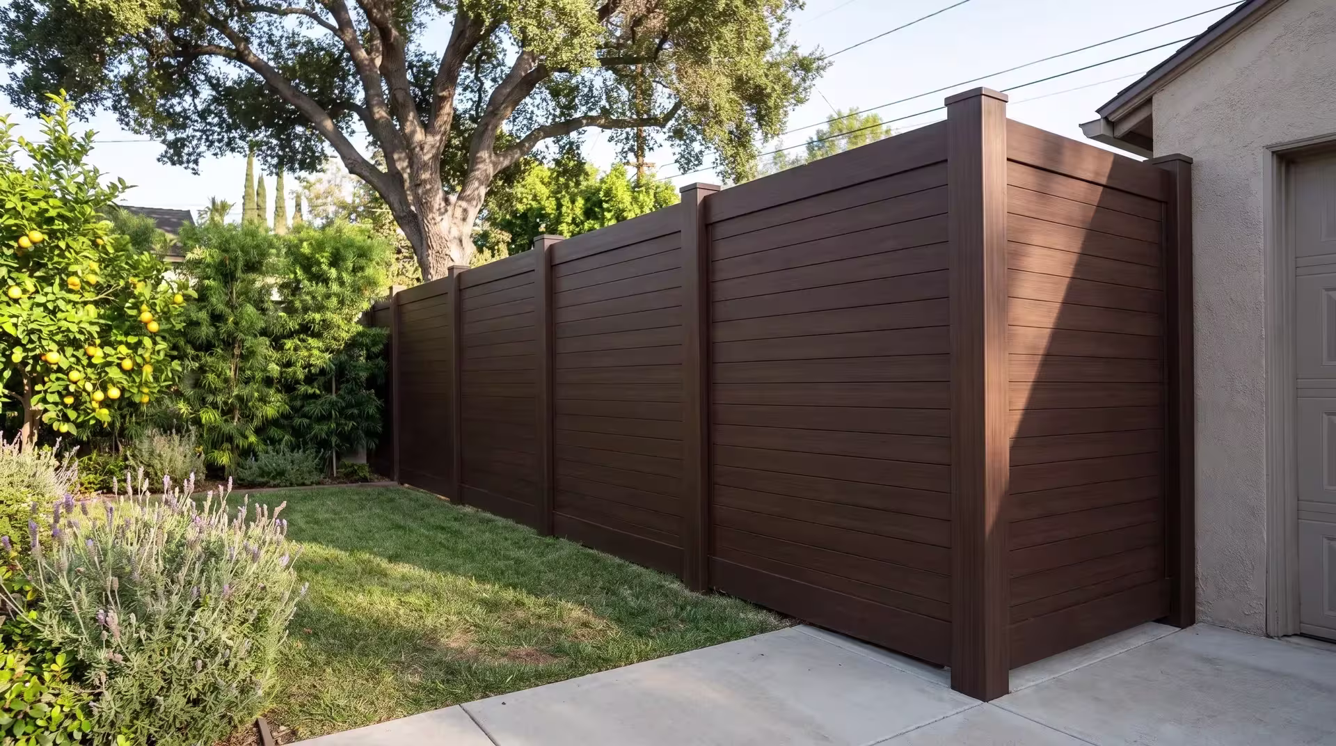 Dark Sequoia vinyl horizontal privacy panels run along a broom-finished concrete walk beneath a mature shade tree