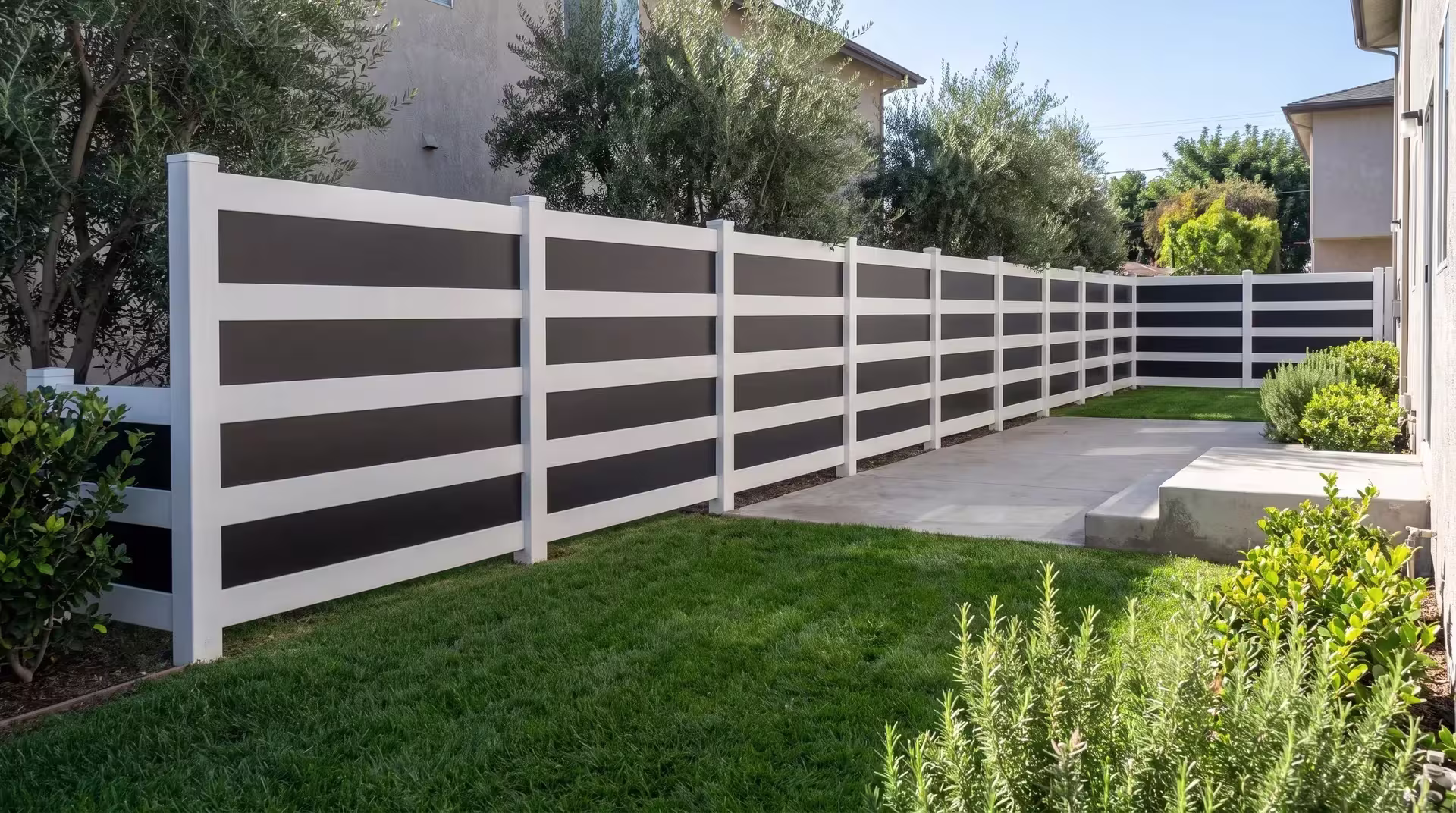 Poured concrete steps and rosemary beds edge a White vinyl privacy fence with acrylic near the patio