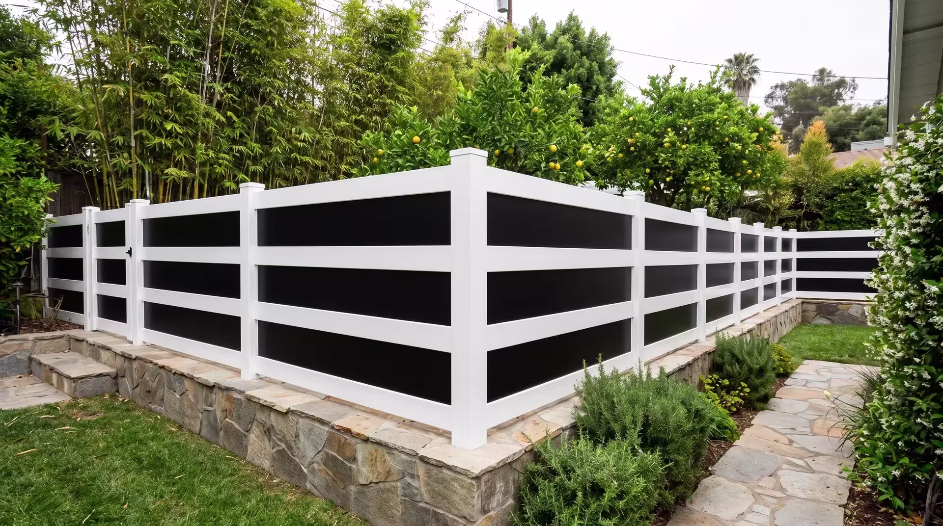 Bamboo screening and star jasmine soften a White vinyl privacy fence with acrylic as it climbs the hillside grade