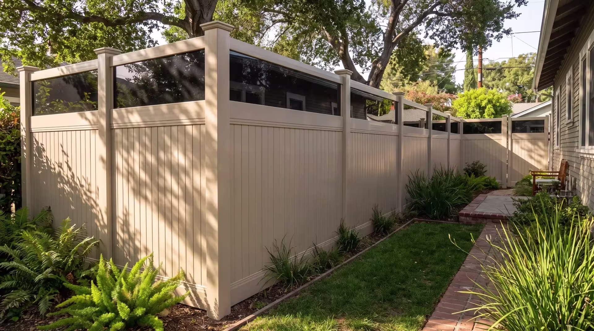 Coast live oak shade falls over a Tan vertical vinyl privacy fence that reaches a clear acrylic top beside a brick path