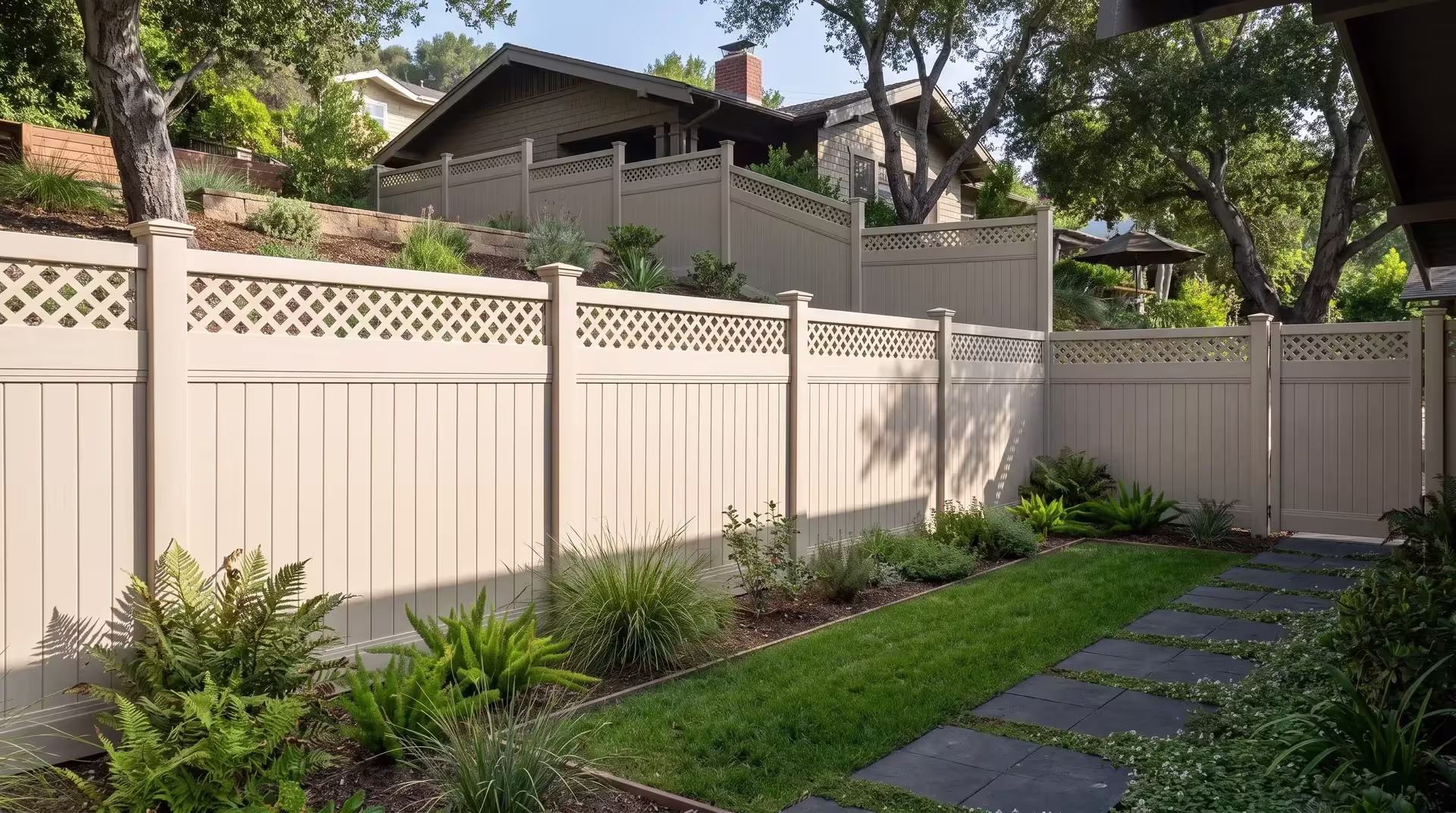 Tan vinyl privacy fence closed out with a lattice section borders a quiet Craftsman bungalow above dark charcoal pavers