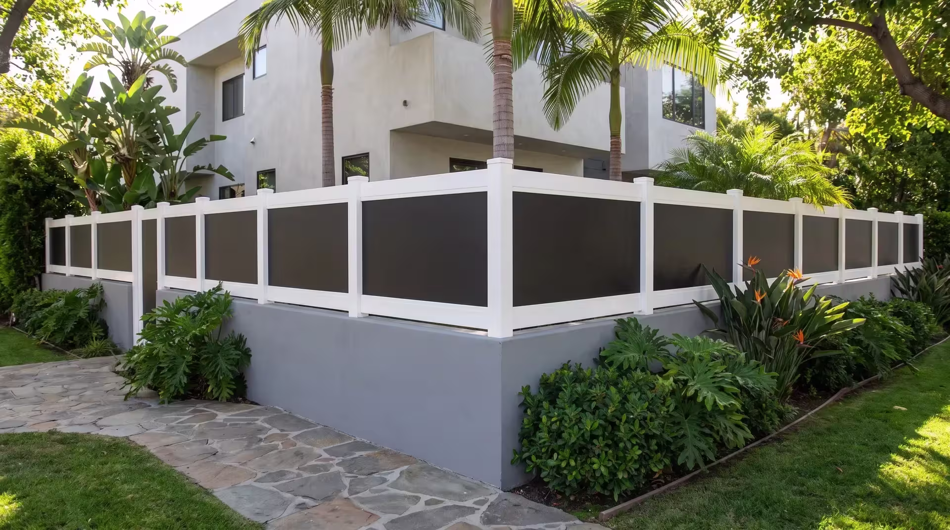 White vinyl wall topper with acrylic caps a painted concrete wall beneath queen palms and bird-of-paradise