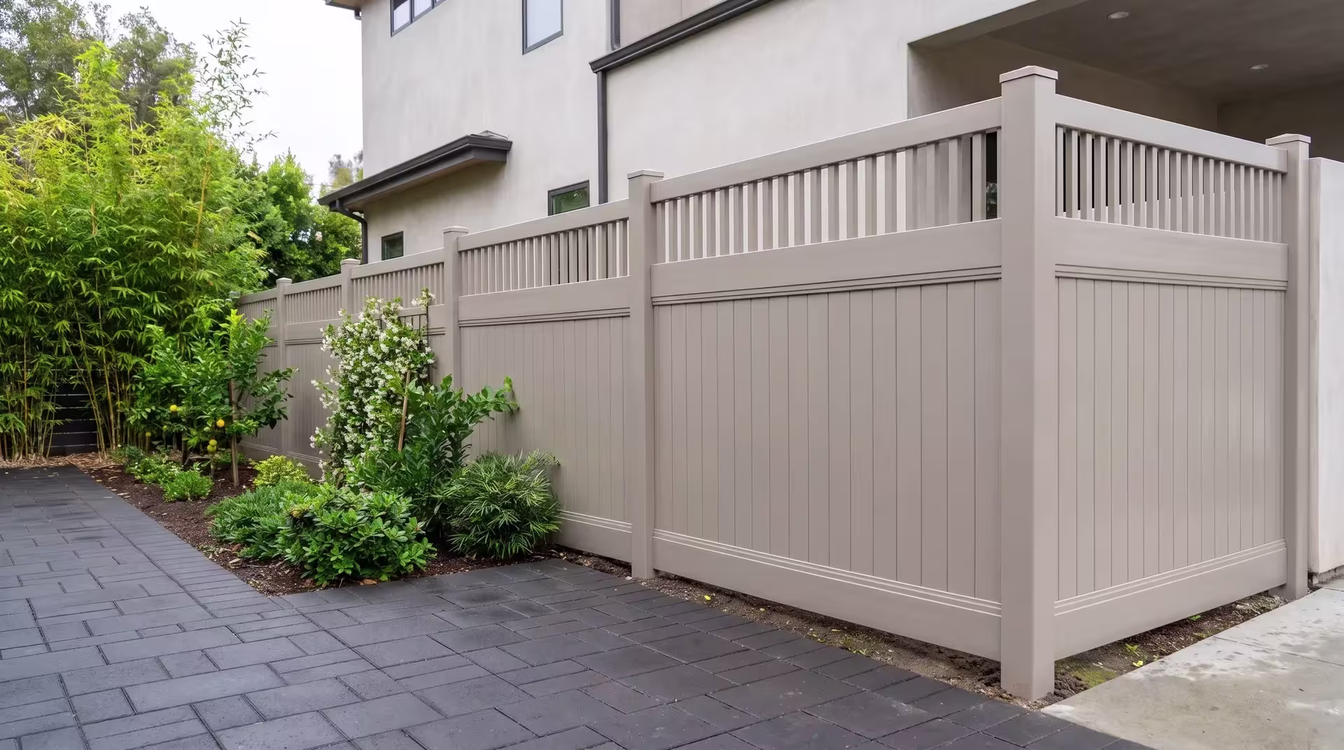 Clay vinyl privacy fence steps down a bamboo-screened front garden, its top finished in pickets