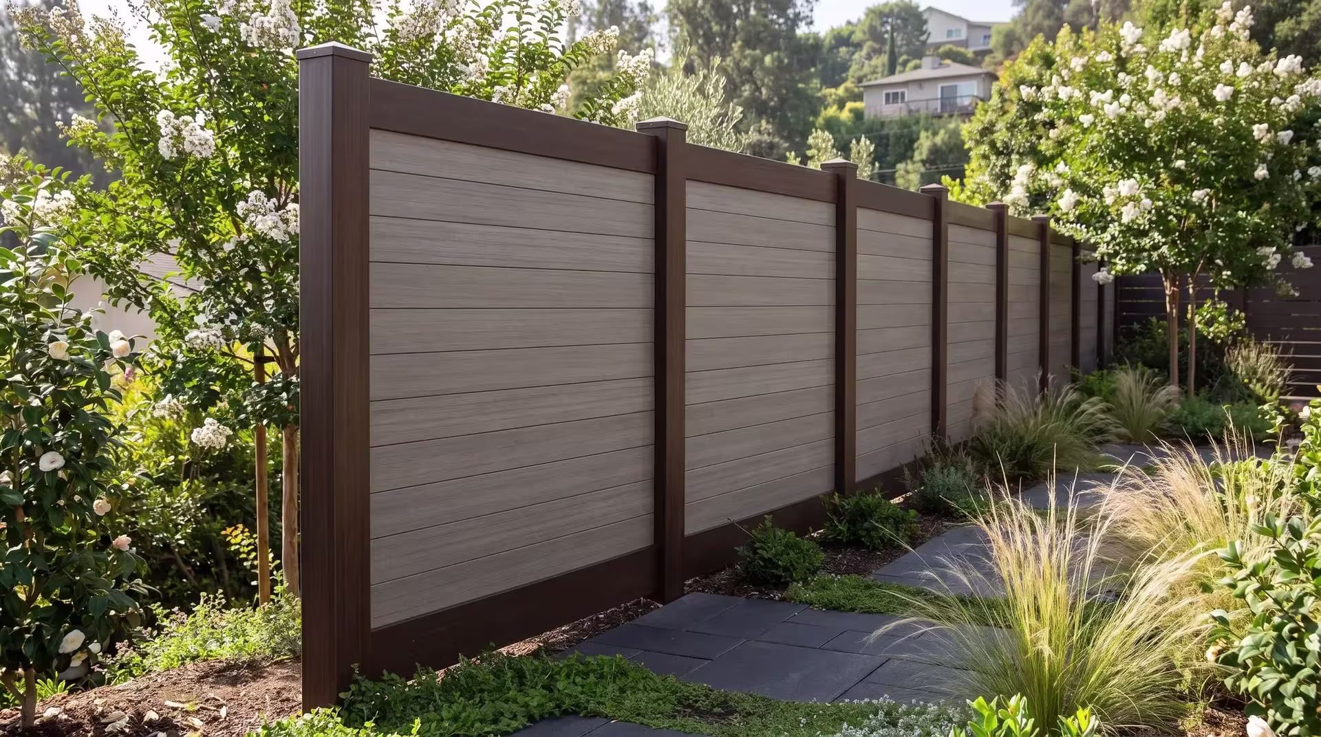 Weathered Blend horizontal boards fill a Dark Sequoia vinyl fence frame beside charcoal pavers and garden planting