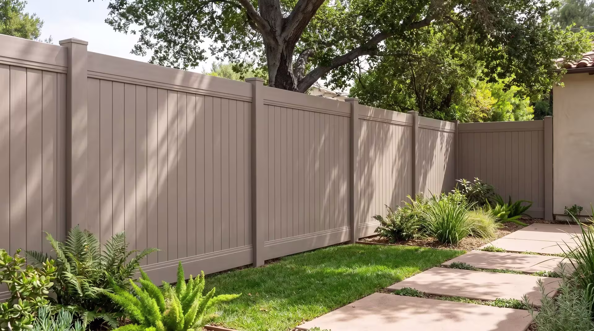 A coast live oak and lomandra bed stand beside this Clay vinyl privacy fence in the deep backyard