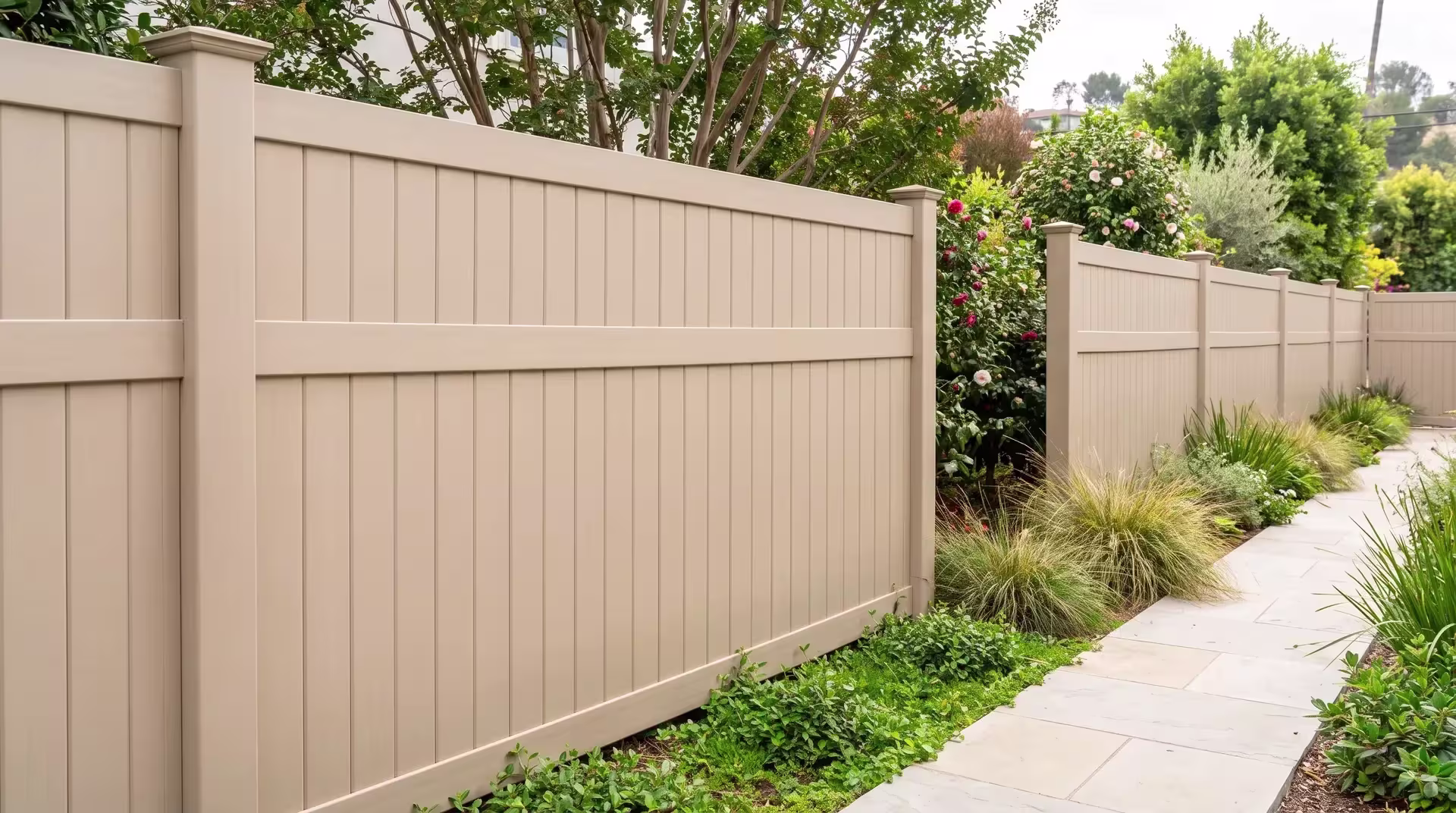 Crepe myrtle and camellias line Tan vinyl vertical privacy fencing along this narrow side yard at a hillside residence
