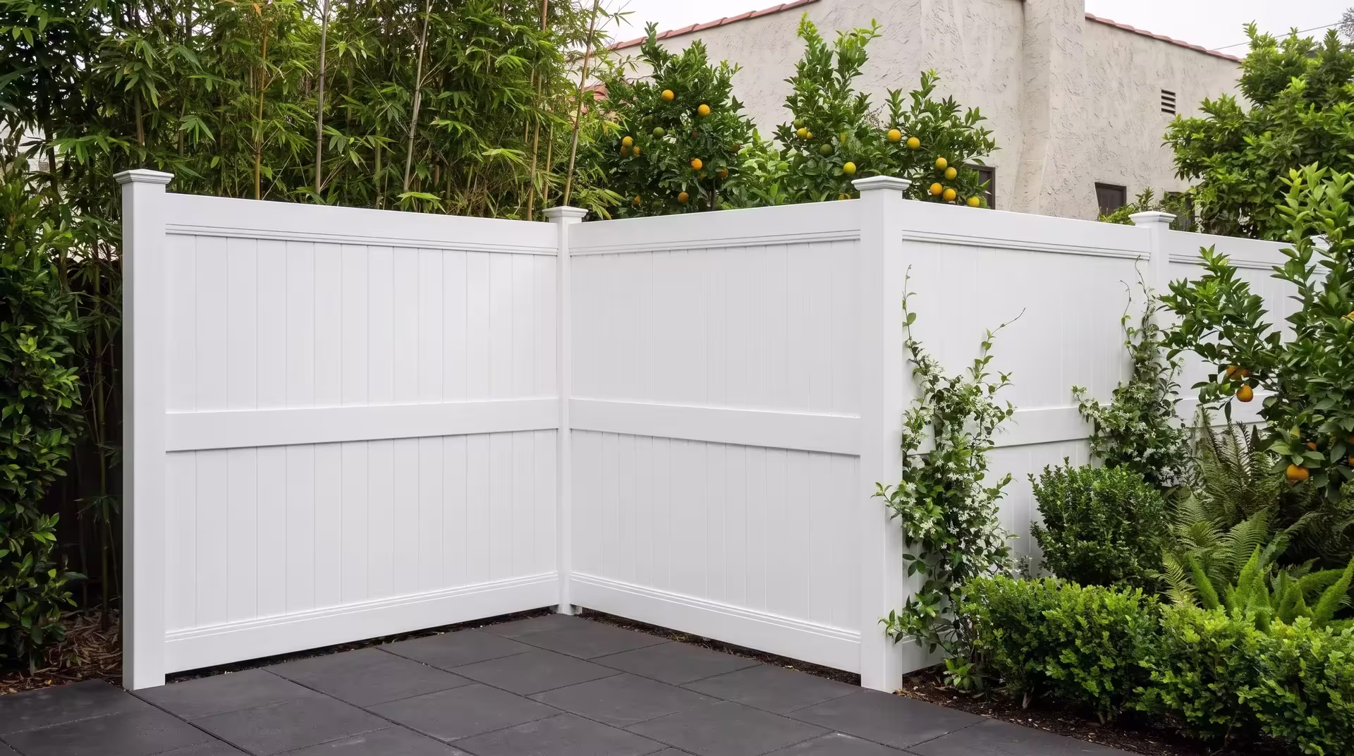 White vinyl fencing with vertical privacy boards wraps a Spanish Revival backyard past bamboo and star jasmine