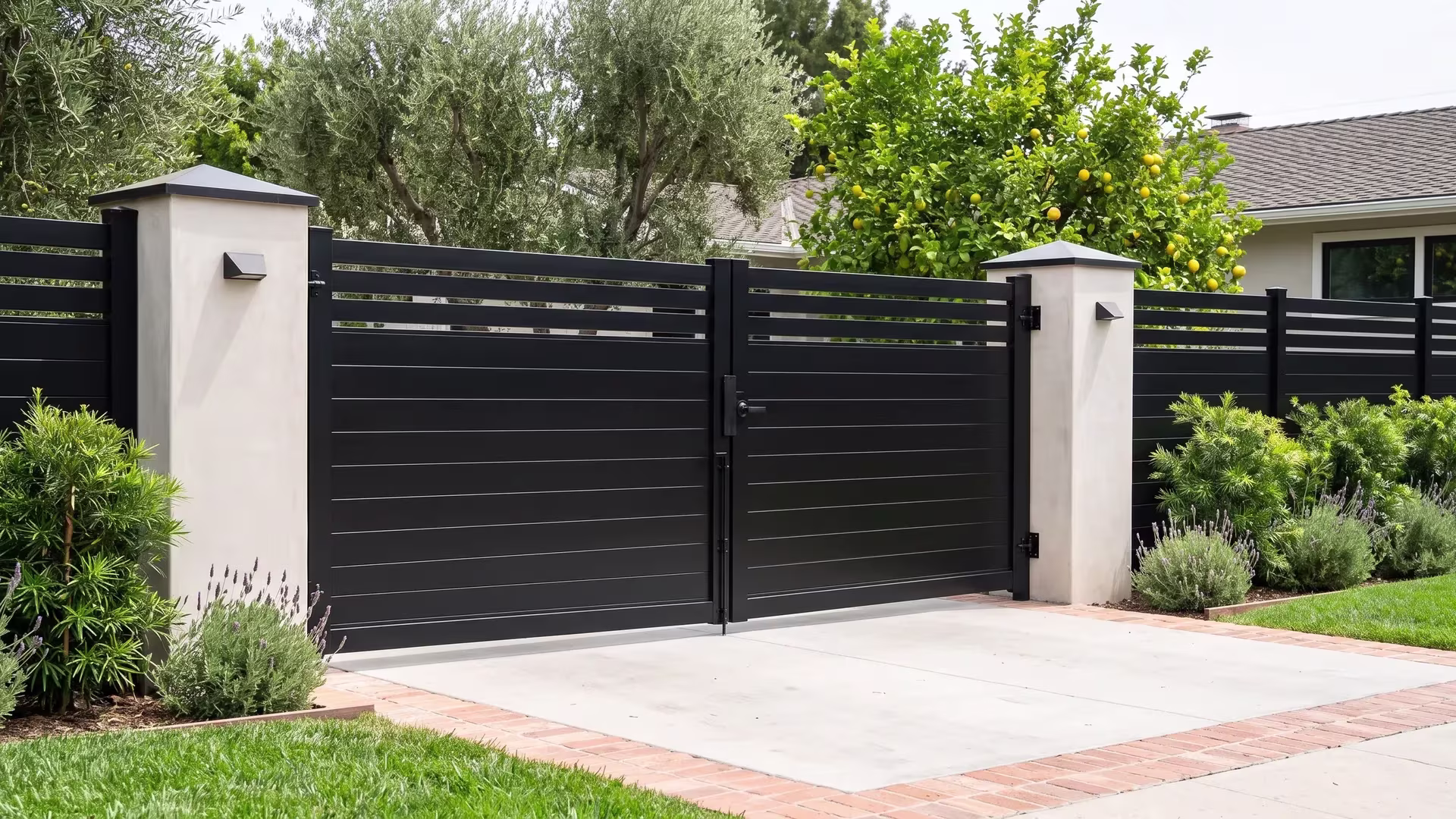 Black privacy hybrid aluminum double gate spanning a brick edged drive to the ranch house entrance