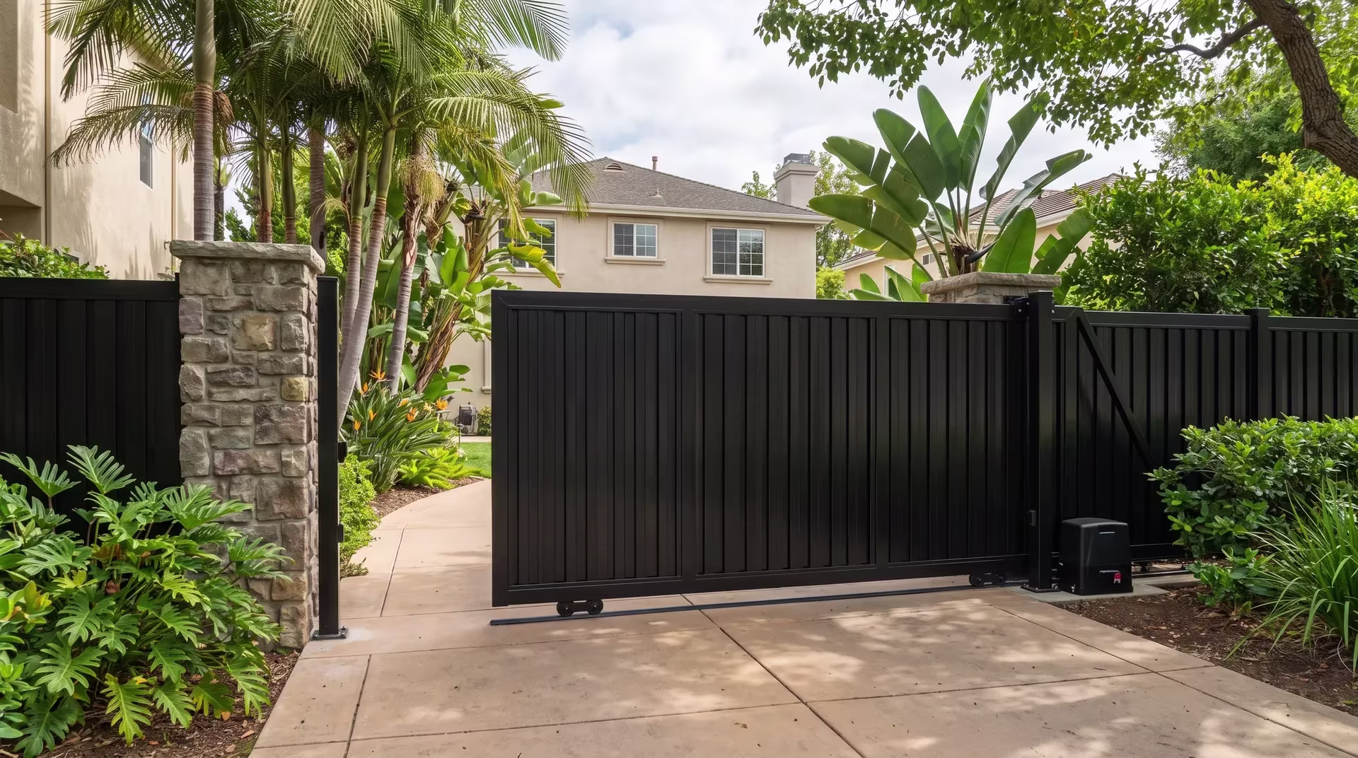 Black aluminum vertical shadowbox rolling gate hung between masonry columns on a service drive