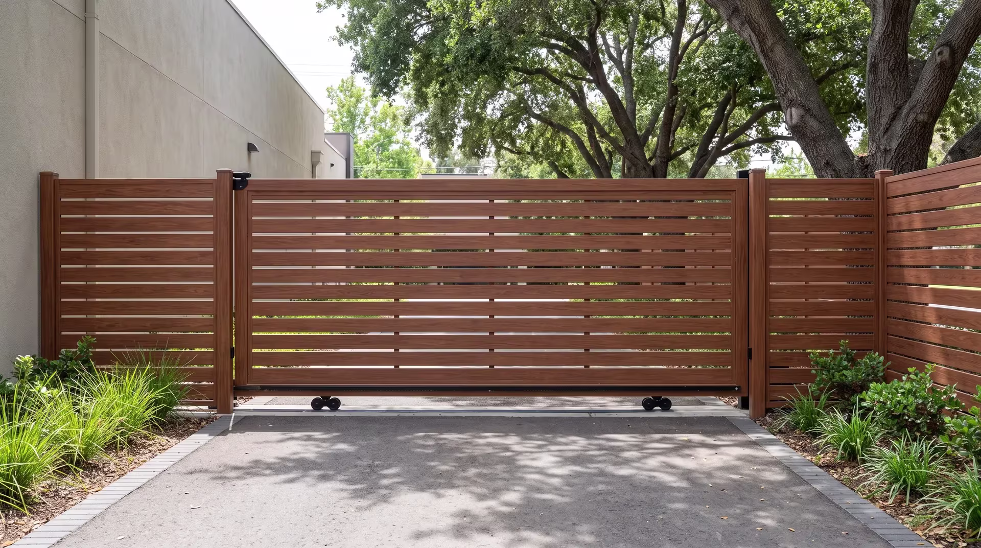 Woodgrain semi privacy aluminum sliding gate opening a rear service drive beneath coast live oak shade